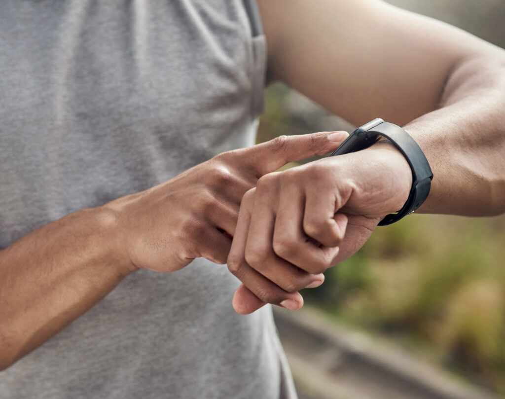 Person checking smartwatch on wrist to track health metrics and daily activity outdoors